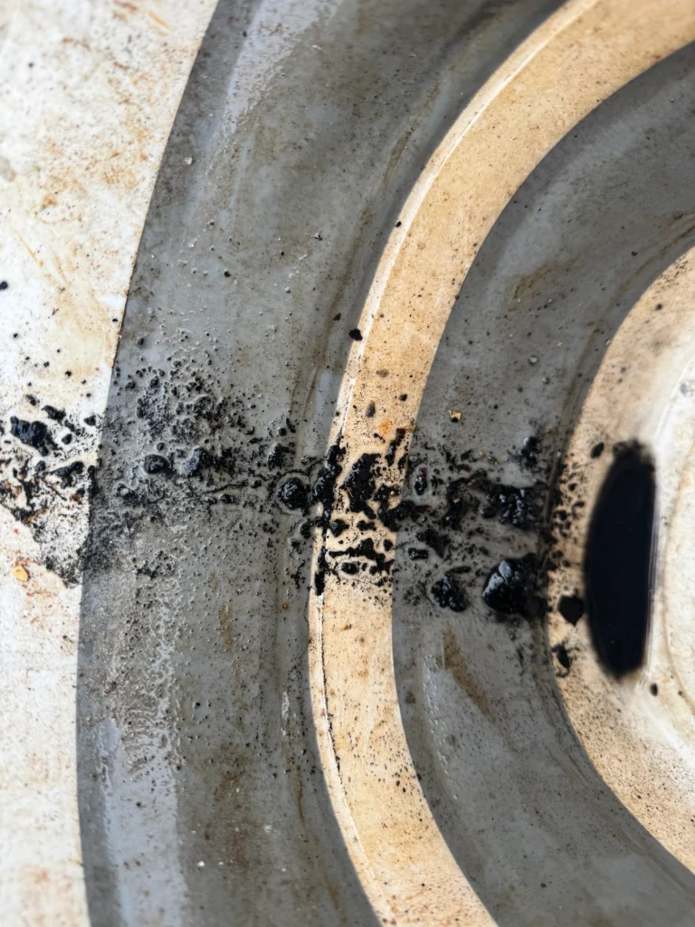 Black debris flushed into a basin while a bathroom drain was cleared