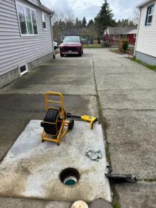 Drain machine staged on a driveway beside an open sewer cleanout at a Bellevue, WA home