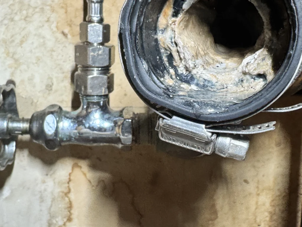 Cut-open sewer pipe showing heavy grease and scale buildup coating the interior wall