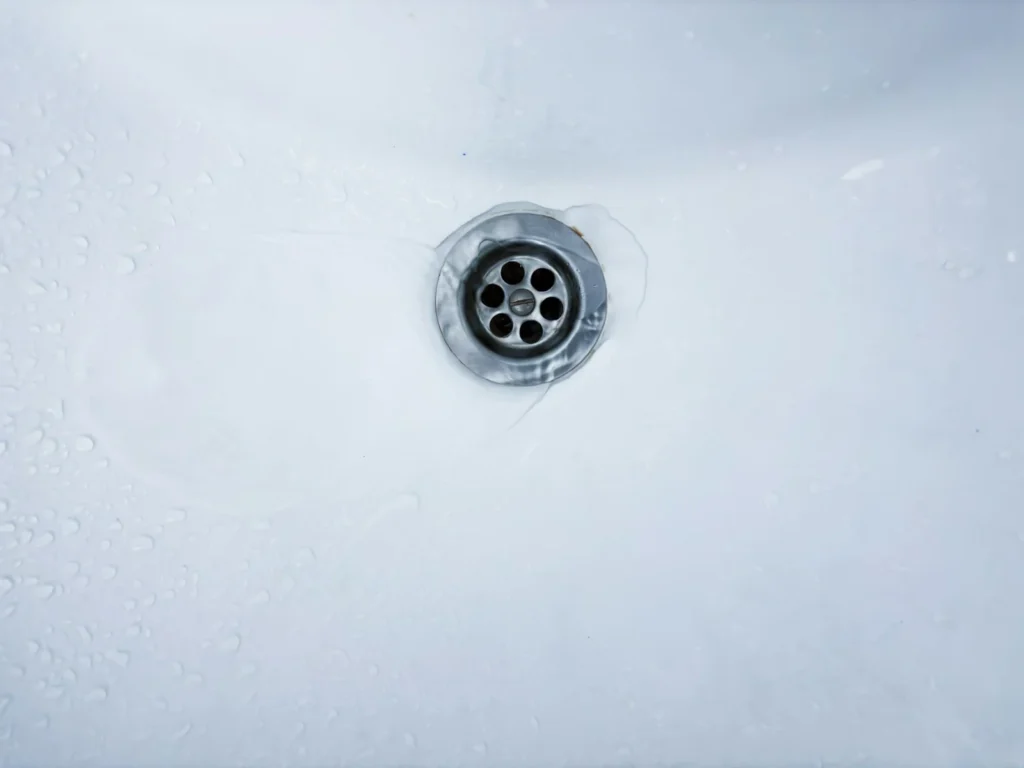 Close view of a bathroom sink drain opening in a white basin