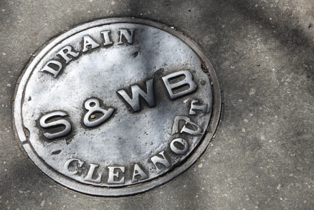 Round metal cover stamped DRAIN S&WB CLEANOUT in a sidewalk