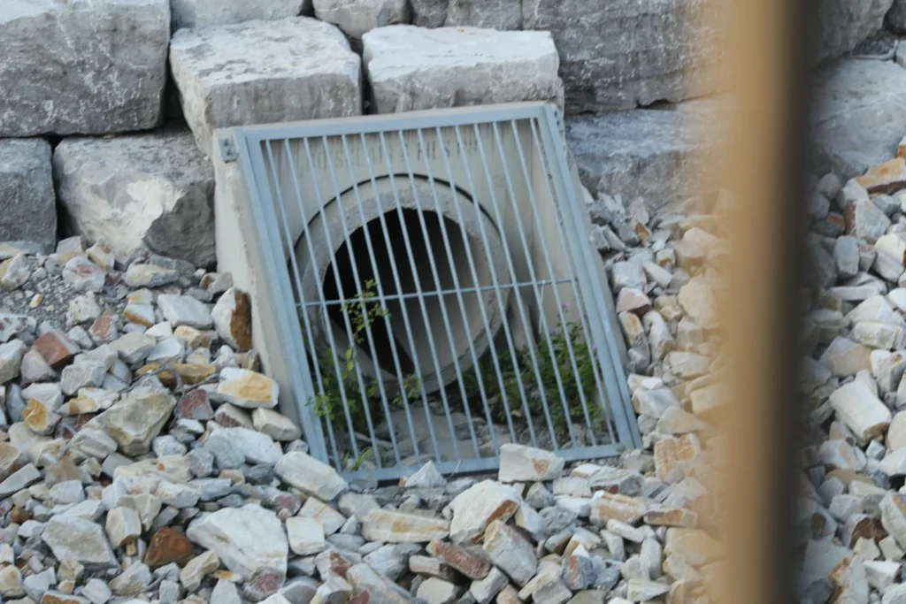 Grated drain outlet set into a rock-lined swale