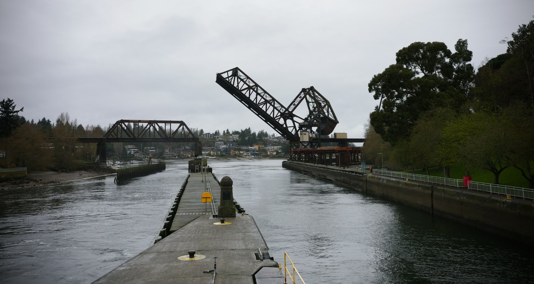 Salmon Bay railroad bascule bridge raised over the Lake Washington Ship Canal, seen from the Ballard Locks on a gray day
